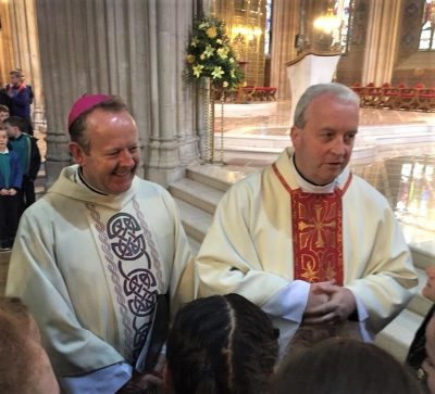 A bishop and a priest standing next to each other in a church.