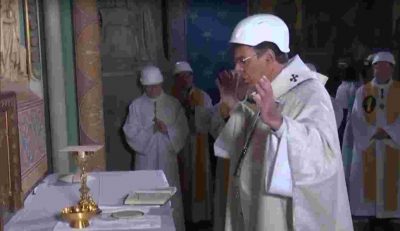 Archbishop in a hard hat celebrating Mass in front of the altar at Notre-Dame Cathedral in Paris.